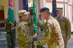 An Italian Army general passes the Resolute Support Mission flag to U.S. Army Gen. Austin S. Miller.