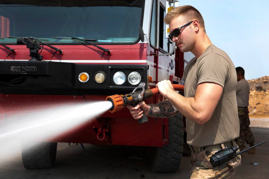 An Air Force airman uses a fire hose during firefighting proficiency training.