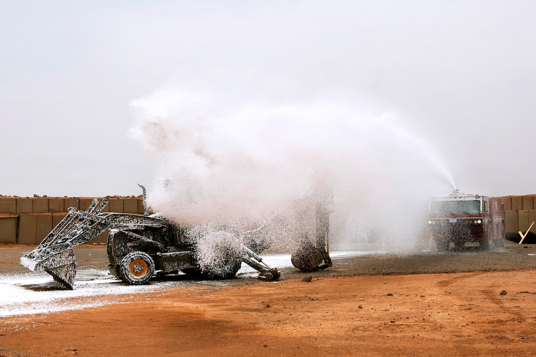 Air Force firefighters operate a P-19B fire truck and use the fire hose to combat a simulated fire.