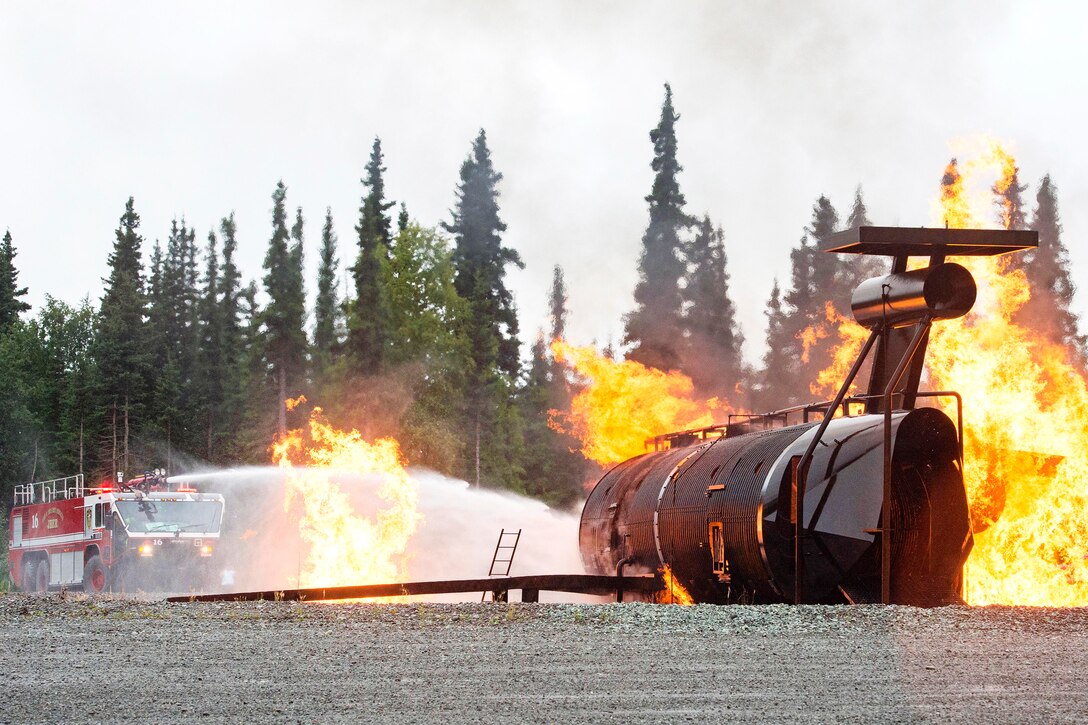 An Air Force firefighting vehicle sprays water on a training fire.
