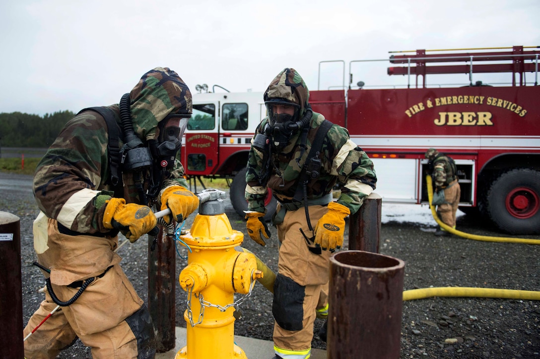 Air Force firefighters turn off a fire hydrant during wartime-firefighting readiness training.