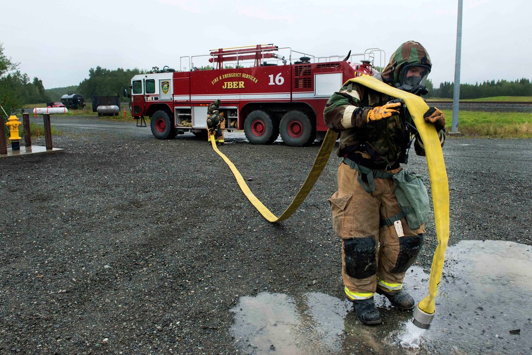 An Air Force firefighter empties a fire hose.