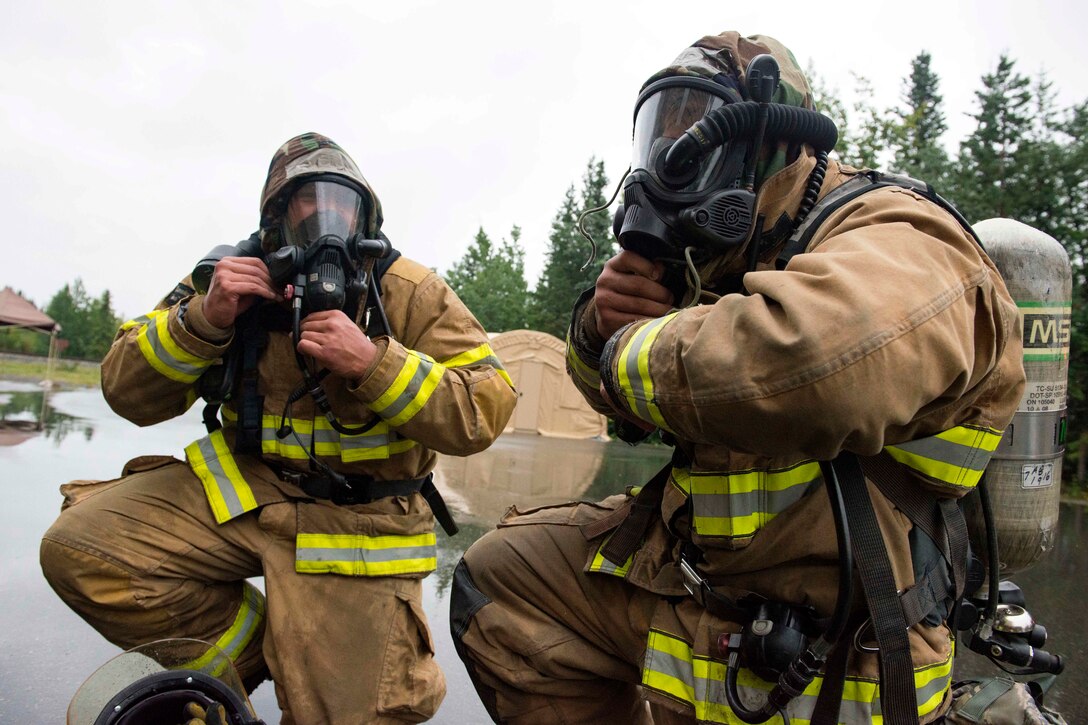 Air Force firefighters remove their protective gear.