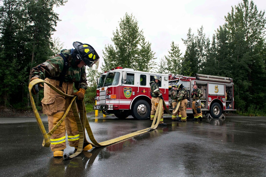 Air Force firefighters put away fire hoses and gear.