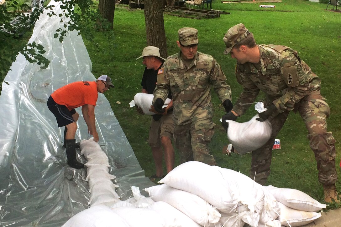 Soldiers and volunteers build a sandbag wall.