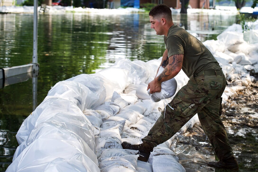 A soldier builds a sandbag wall.