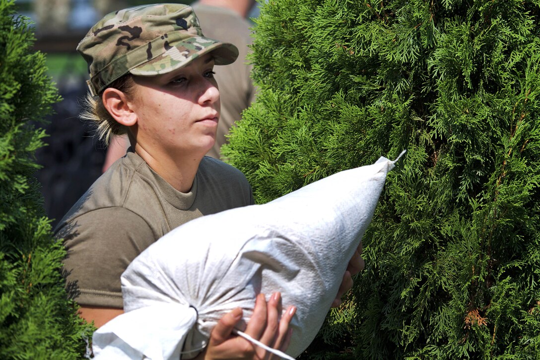 A soldier carries a sandbag.