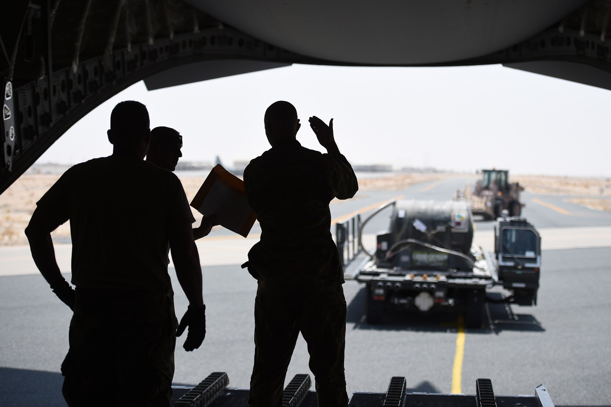Airmen push cargo in the back of a C-17.