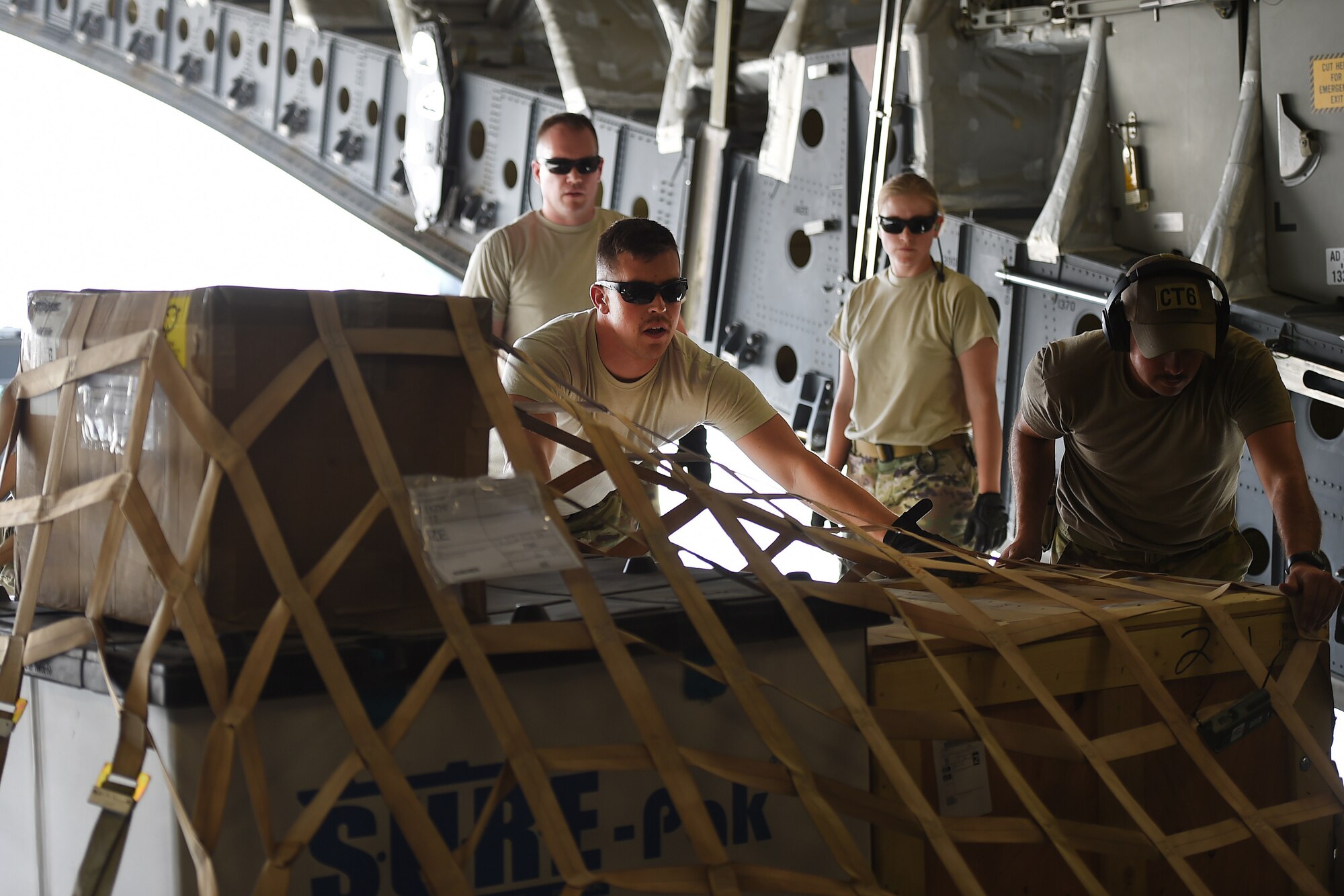 Airmen push cargo in the back of a C-17.