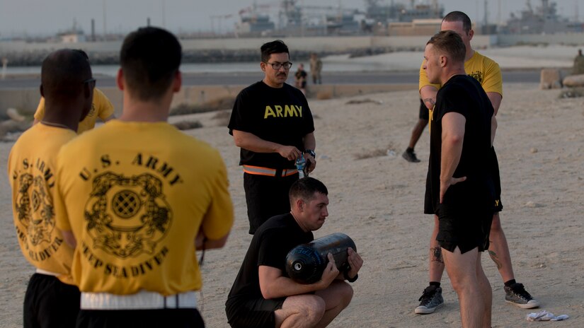A U.S. Army Soldier squats with an air tank before handing it to his teammate at the 74th Engineer Dive Detachment's Diver Fitness Challenge at Kuwait Naval Base, Kuwait, Aug. 31, 2018. The Soldiers who participated in the Diver Fitness Challenge exemplified the U.S. Army's enduring commitment to excellence.