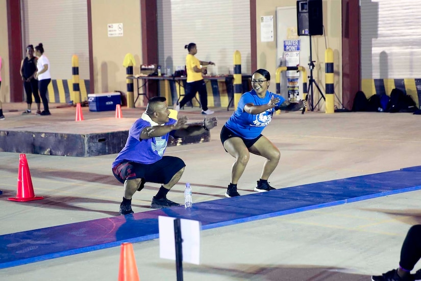 Two Soldiers share a smile during a squat exercise at the Sisters in Arms circuit training event at Camp As-Sayliyah, Qatar, August 23, 2018.  Each participant had a battle buddy to encourage him/her during the exercises.