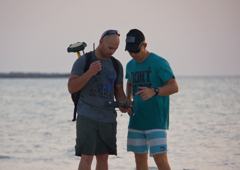 U.S. Army Staff Sgt. Richard Lee, left, a 1st class diving supervisor and U.S. Army Sgt. Daniel Byrd, a 2nd class diver survey the shoreline on foot in water too shallow for waterborne vessels near Abu Dhabi, Aug 4, 2018. These measurements, along with depths recorded in deeper water with hydrographic survey equipment, will be used to assist Trident Pier placement and boat operations conducted in this stretch of the Gulf off the coast of Abu Dhabi.
