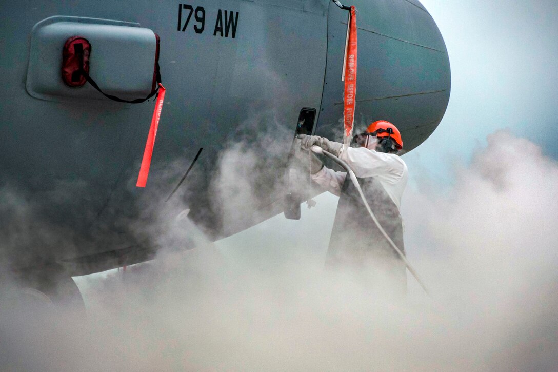 An airman refills the liquid oxygen tank in an aircraft.