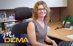 Smiling female sits at her desk looking at the camera.