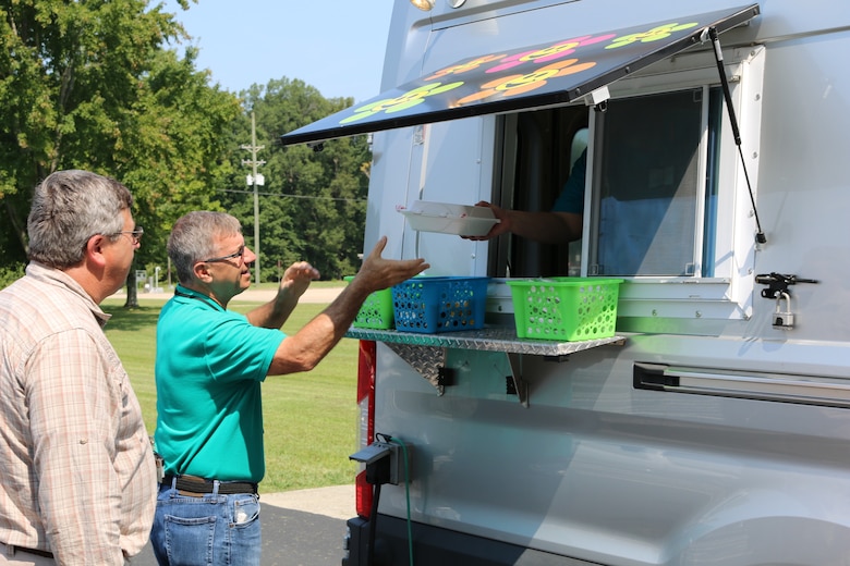 Gene Klingensmith, center, picks up his order from the Crazy Daisies food truck. Klingensmith was among those who visited the food truck during its first day of operations at Arnold Air Force Base. (U.S. Air Force photo by Bradley Hicks)