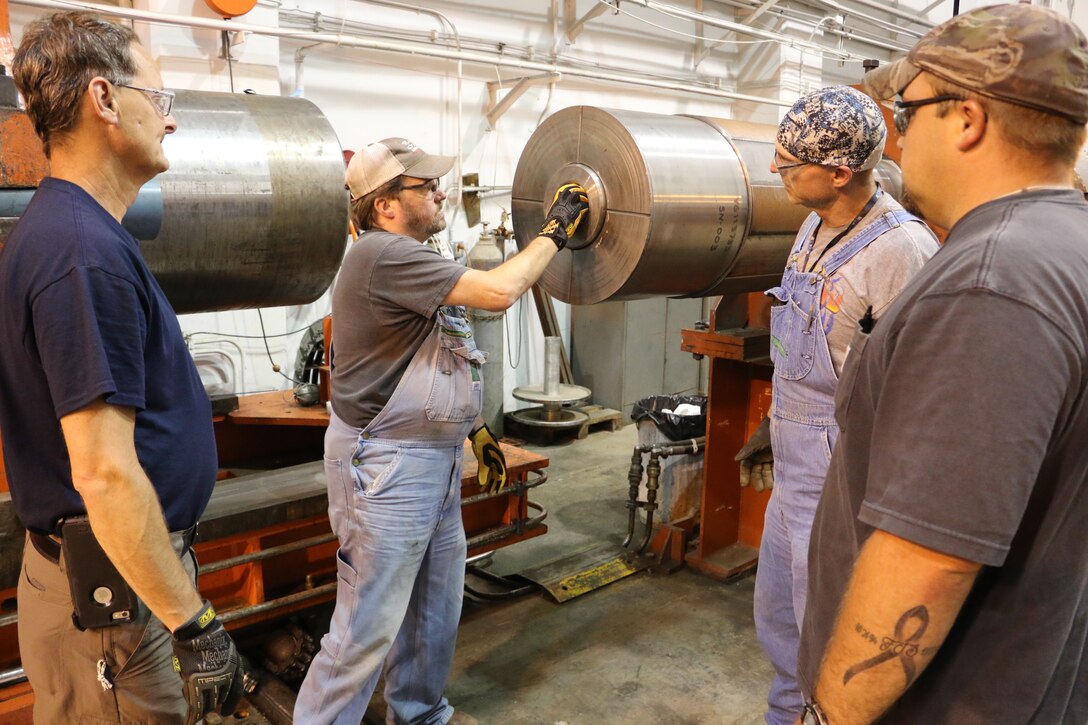 Outside machinists Tim Gilliam, left, and Will Jacques, right, and boilermaker Troy Caldwell, second from right, look on as Lead Outside Machinist Mark Carson loads a projectile into the launcher. The craftsmen are helping to improve weather encounter testing at the range. (U.S. Air Force photo by Bradley Hicks)