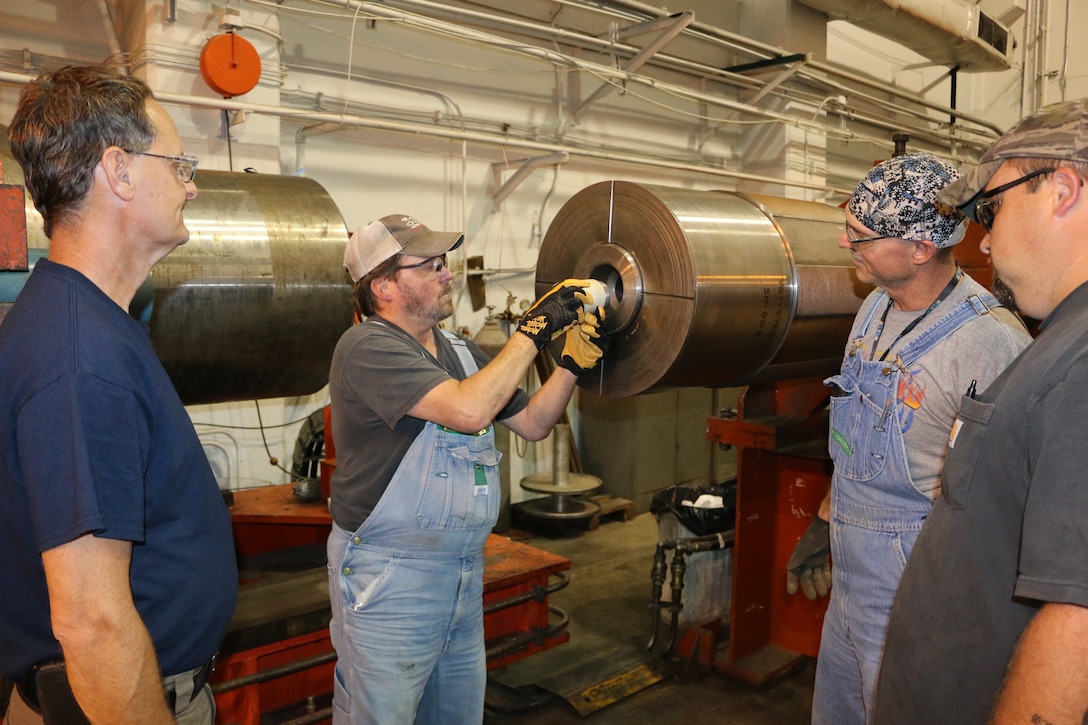 Outside machinists Tim Gilliam, left, and Will Jacques, right, and boilermaker Troy Caldwell, second from right, look on as Lead Outside Machinist Mark Carson loads a projectile into the launcher. The craftsmen are helping to improve weather encounter testing at the facility. (U.S. Air Force photo by Bradley Hicks)