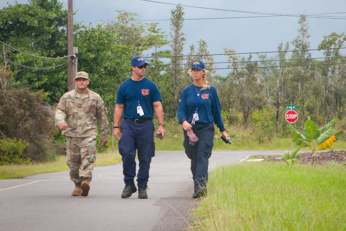 Three people walk along a road in Hawaii.