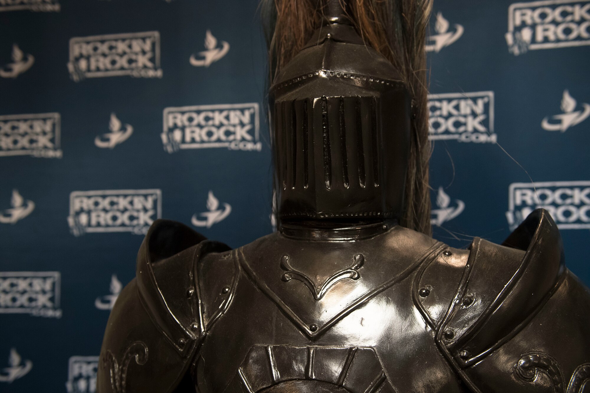 A suit of armor is posed in front of a backdrop.