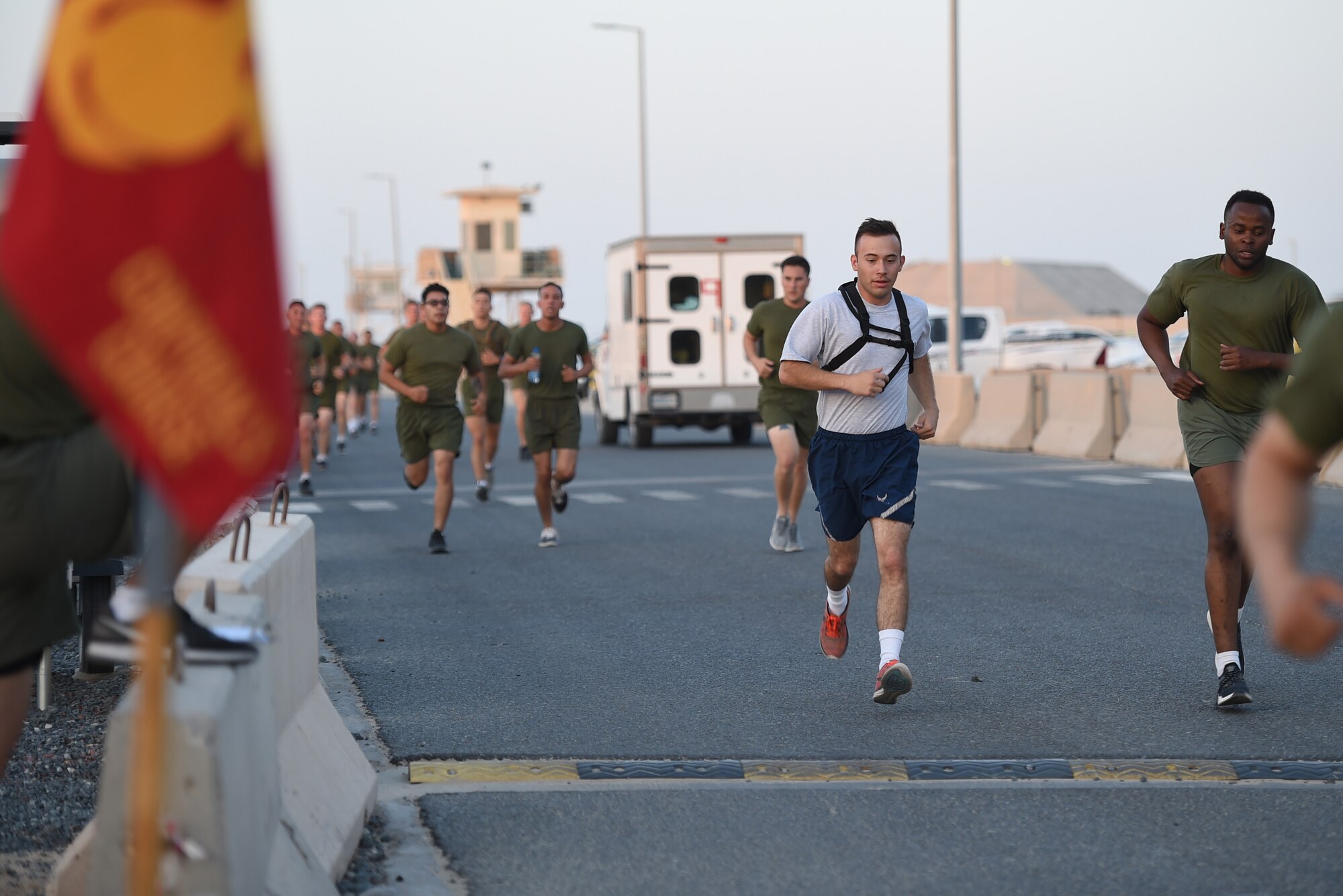 An Airman runs next to Marines