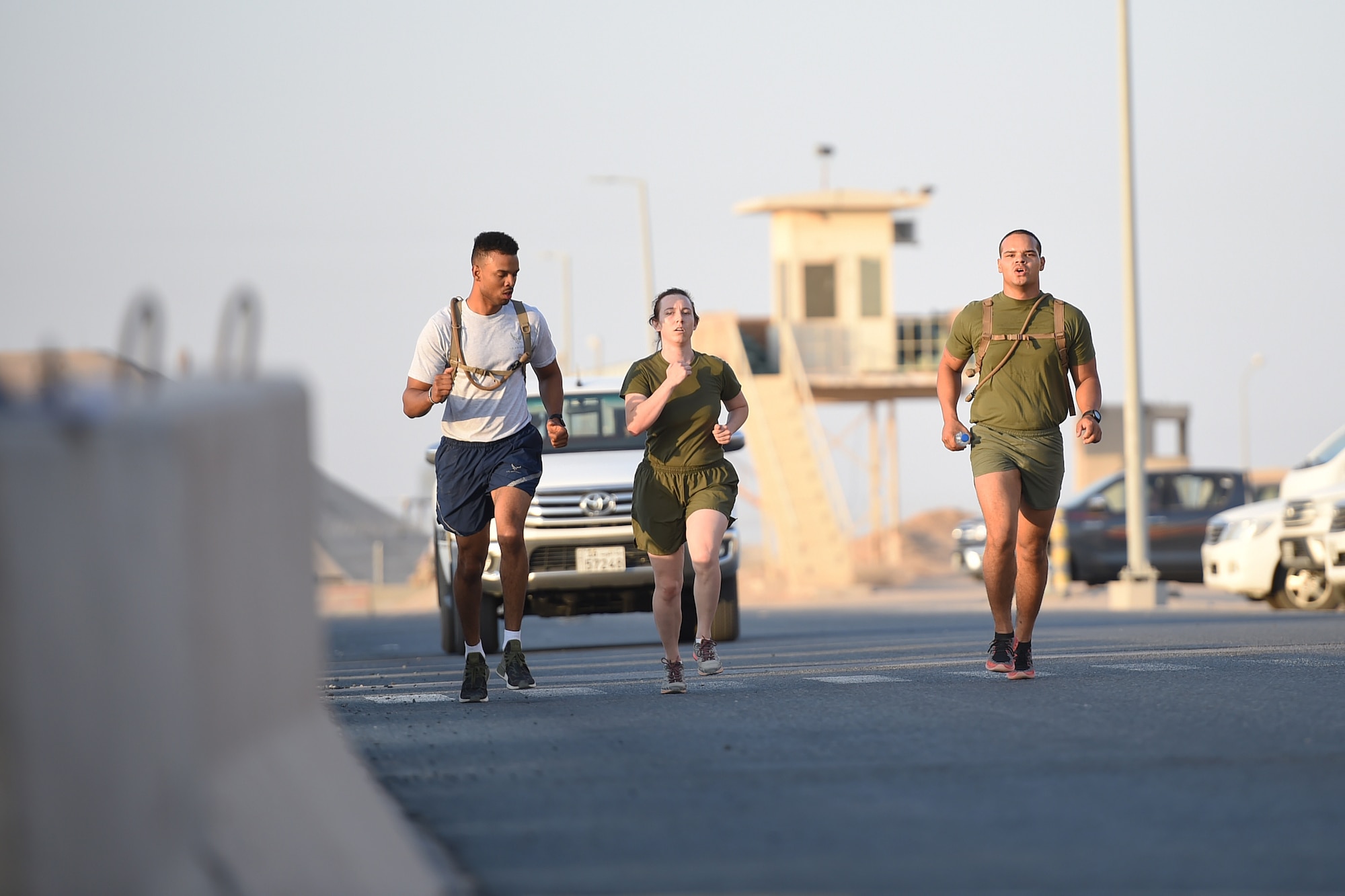 An Airman runs next to two Marines