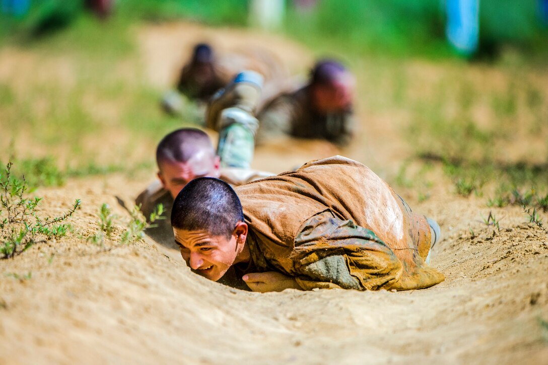 Soldiers in a line crawl along a sandy path.