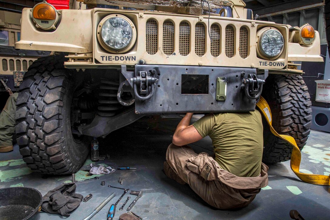 A Marine works on a Humvee.