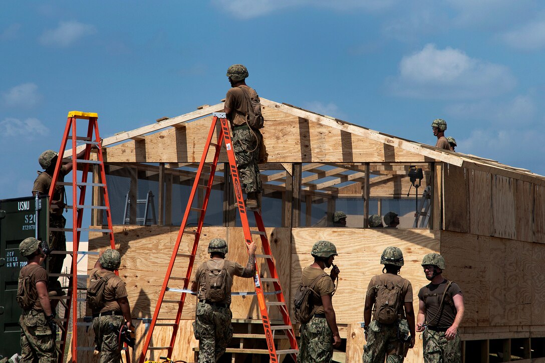 Sailors work on the roof while constructing a building.