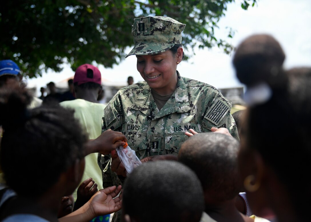 A U.S. Navy sailor  hands out candy to local children at Gimnasio Cristiano de Bocachica children’s school.