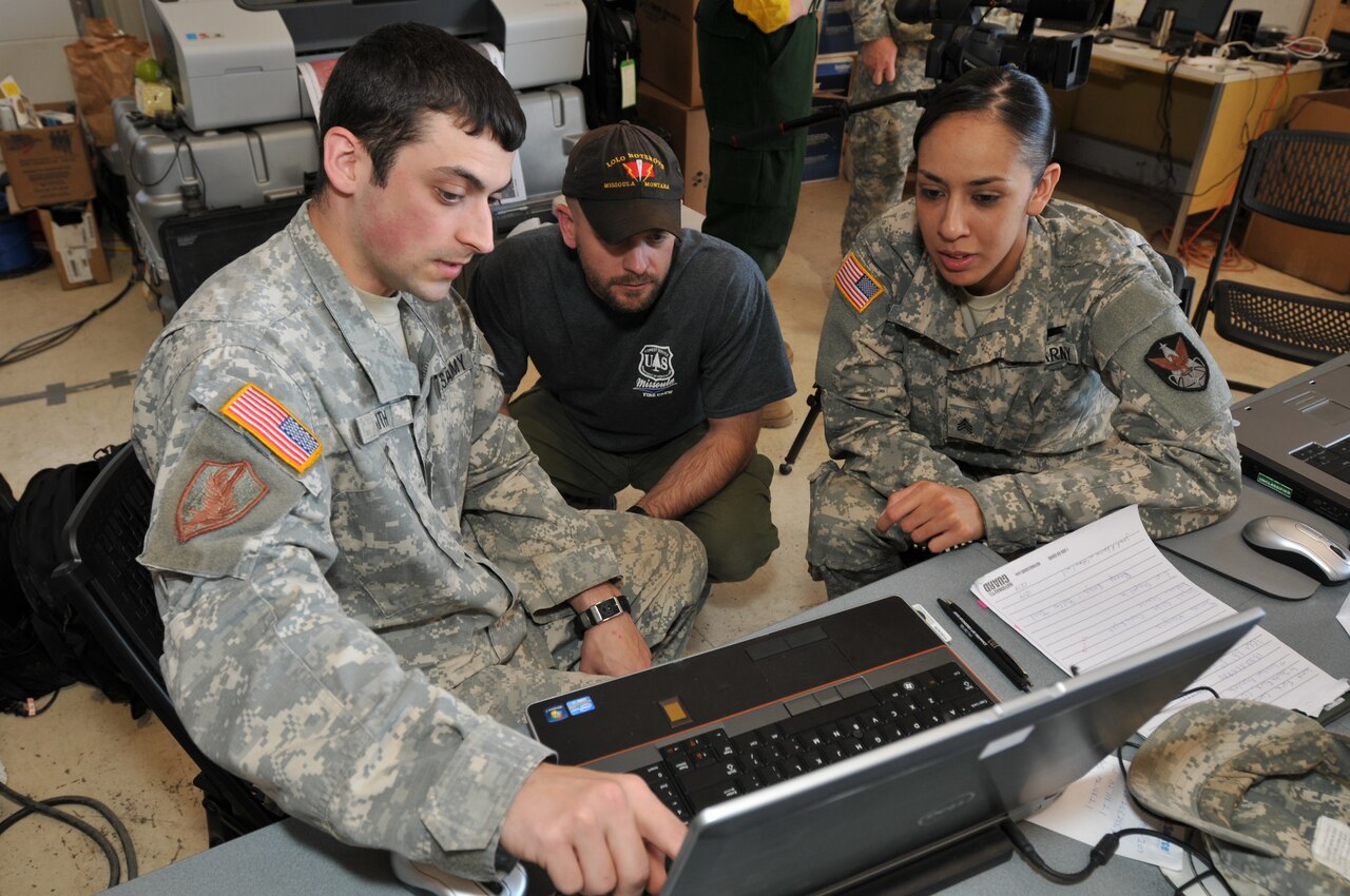 Colorado Army National Guard Sgts. Nathan Faith and Cassandra Quinones discuss an infrared satellite image of the West Fork Complex wildfire with Matt Gibson of the U.S. Forest Service's Lolo Interagency Hotshot Crew from Missoula, Mont.