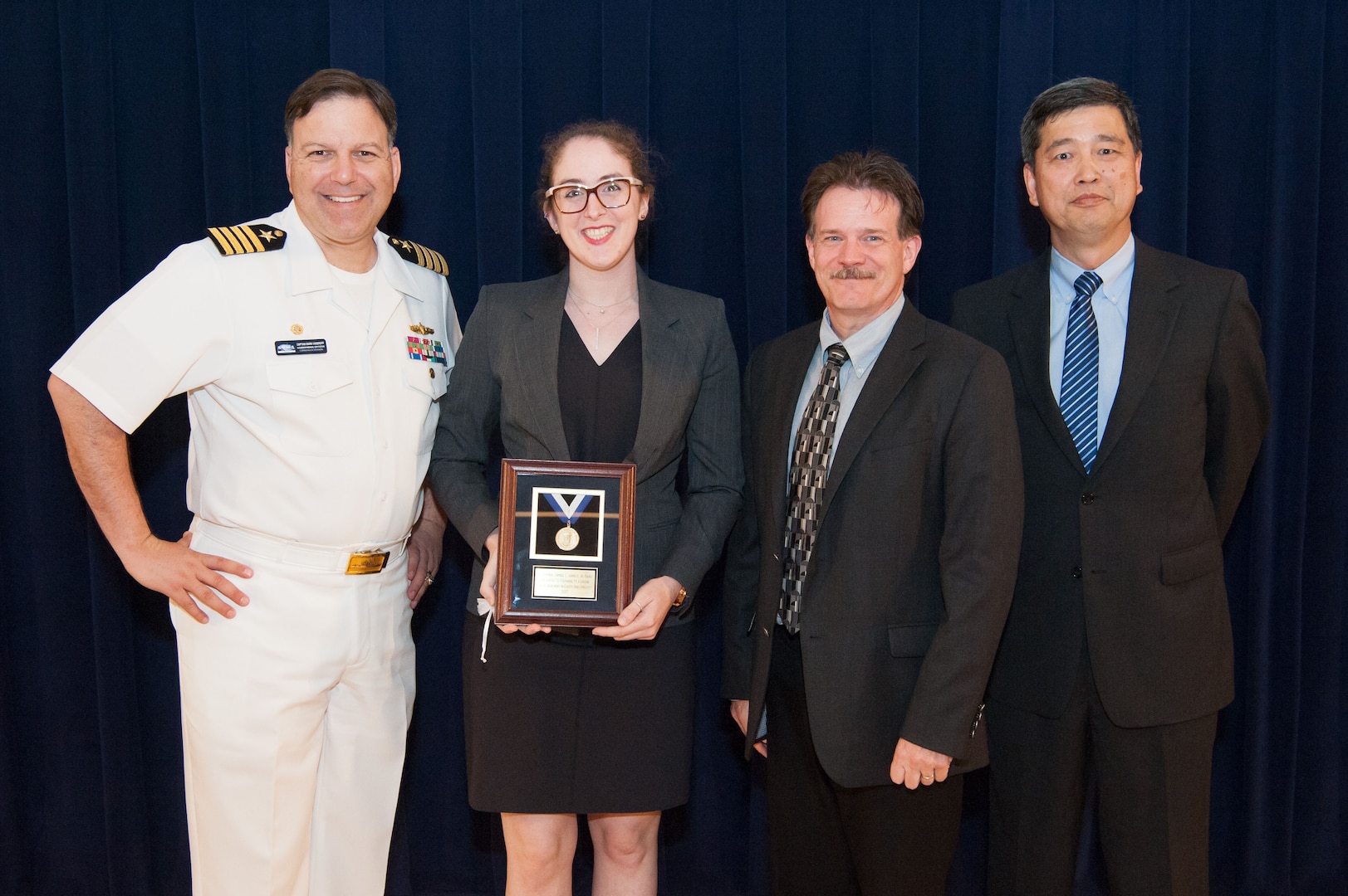 Stephanie Ferrone, a physicist in Carderock's Underwater Electromagnetic Signatures and Technology Division, receives the Vice Adm. Samuel L. Gravely Jr. Award for achievement in equity and diversity at the Naval Surface Warfare Center, Carderock Division Honor Awards ceremony Aug. 28, 2018, in West Bethesda, Md. From left to right: Commanding Officer Capt. Mark Vandroff; Ferrone; Mike Slater, division head of Carderock's Signatures Measurement Technologies and Systems Division; and Paul Shang, Carderock's acting technical director. (U.S. Navy photo by Nicholas Brezzell/Released)