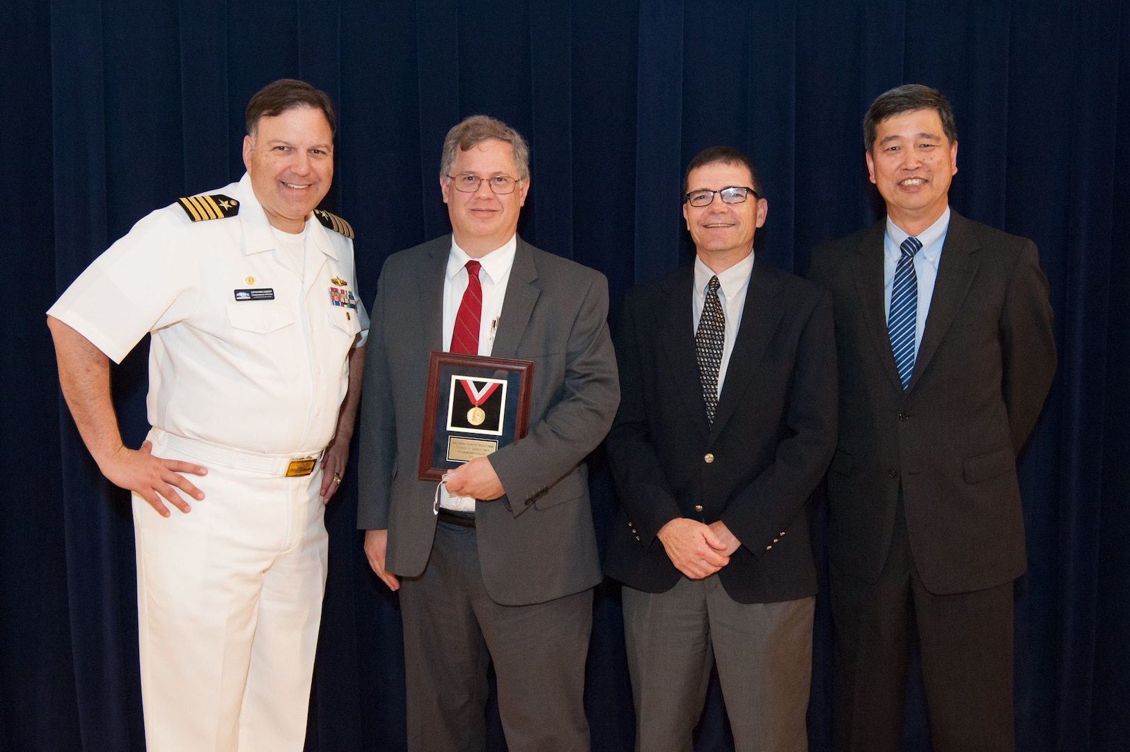 Stephen Neely, a naval architect in Carderock's Computational Propulsors Branch, receives the Rear Adm. George W. Melville Award for engineering excellence at the Naval Surface Warfare Center, Carderock Division Honor Awards ceremony Aug. 28, 2018, in West Bethesda, Md. From left to right: Commanding Officer Capt. Mark Vandroff; Scott Black, accepting on Neely™s behalf; Steve Ouimette, deputy head of the Naval Architecture and Engineering Department; and Dr. Paul Shang, acting technical director. (U.S. Navy photo by Nicholas Brezzell/Released)