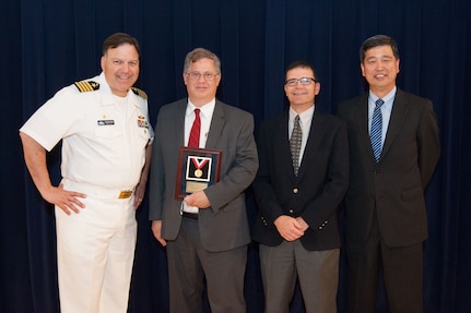 Stephen Neely, a naval architect in Carderock's Computational Propulsors Branch, receives the Rear Adm. George W. Melville Award for engineering excellence at the Naval Surface Warfare Center, Carderock Division Honor Awards ceremony Aug. 28, 2018, in West Bethesda, Md. From left to right: Commanding Officer Capt. Mark Vandroff; Scott Black, accepting on Neely™s behalf; Steve Ouimette, deputy head of the Naval Architecture and Engineering Department; and Dr. Paul Shang, acting technical director. (U.S. Navy photo by Nicholas Brezzell/Released)