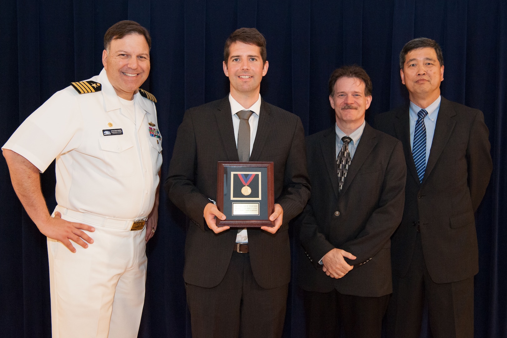 Dr. Brian Glover, a physicist in Carderock's Theory, Modeling and Analysis Branch, receives the Rear Adm. David W. Taylor Award for outstanding scientific achievement at the Naval Surface Warfare Center, Carderock Division Honor Awards ceremony Aug. 28, 2018, in West Bethesda, Md. From left to right: Commanding Officer Capt. Mark Vandroff; Glover; Mike Slater, division head of Carderock's Signatures Measurement Technologies and Systems Division; and Dr. Paul Shang, acting technical director. (U.S. Navy photo by Nicholas Brezzell/Released)