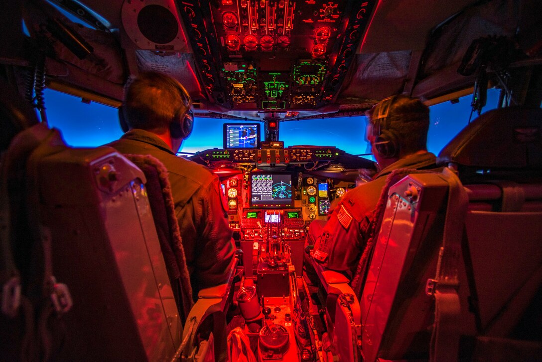Two pilots sit in a cockpit.