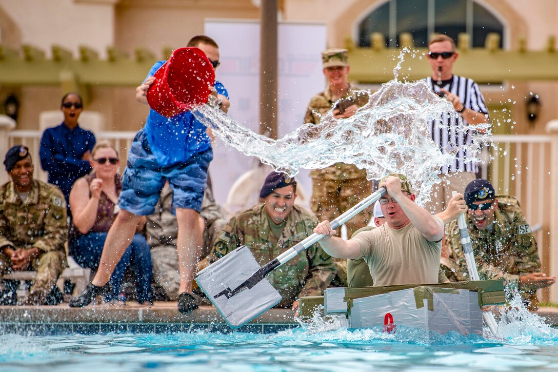 Airmen try to avoid getting splashed while paddling a canoe in a pool