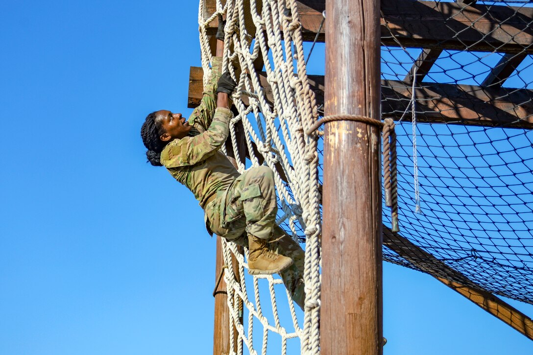 An airman climbs a rope net.