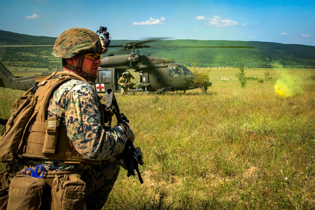 A Marine provides security while an Army helicopter waits to transport a mock casualty.