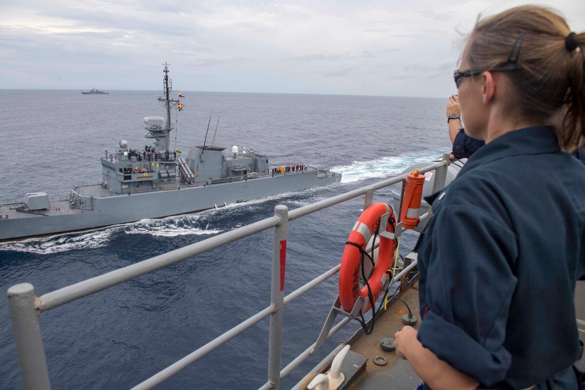 A U.S. Navy officer on USS Gunston Hall observes as the ARC Almirante Padilla sails alongside.