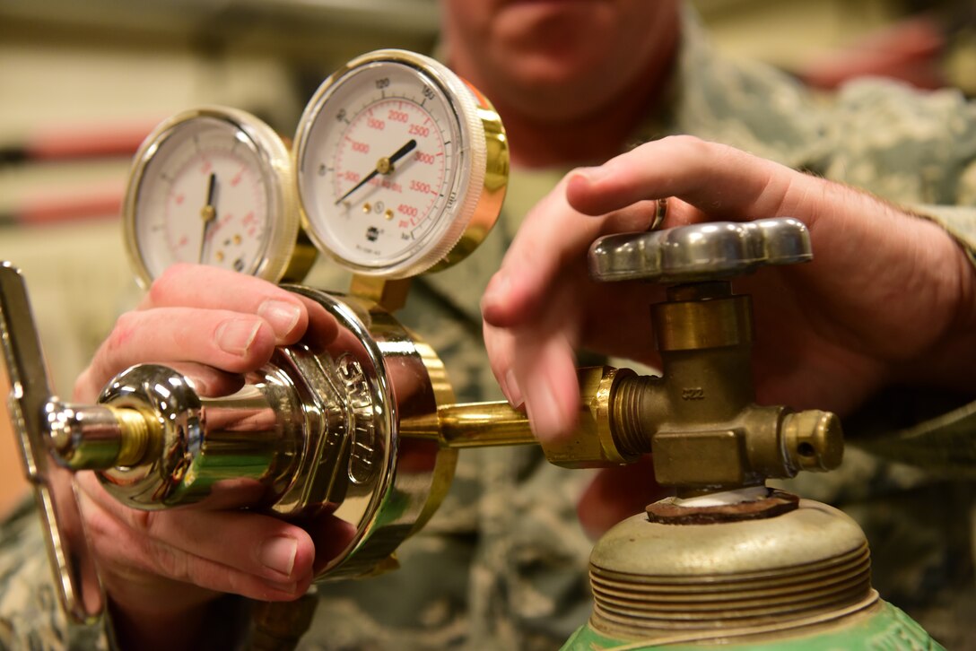 Master Sgt. Brandon Cotter, the 28th Maintenance Squadron metals technology shop section chief, fits a pressure guage to an oxygen bottle at Ellsworth Air Force Base, S.D., Aug. 23, 2018. The metals technology shop runs 24-hour operations to provide different metals technologies for all squadrons on base. (U.S. Air Force photo by Airman John Ennis)