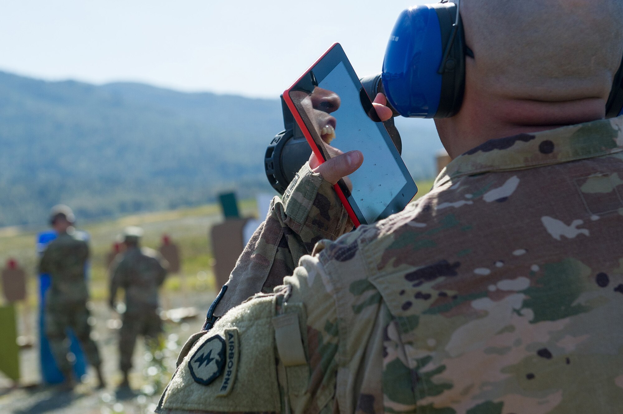 Army Chief Warrant Officer 2 William Orozco, assigned to the 6th Brigade Engineer Battalion (Airborne), 4th Infantry Brigade Combat Team (Airborne), 25th Infantry Division, U.S. Army Alaska, is seen reflected in a mobile device as he yells out a target ‘hit’ during the first day of the America’s First Corps 2-Gun Sharpshooter Competition sponsored by U.S. Army Alaska's Sharpshooter Team at the Joint Base Elmendorf-Richardson, Alaska, Range Complex, Sept. 5, 2018.  Ten five-soldier teams assigned to multiple units throughout I Corps will compete in six stages of competition over two days with U.S. Army issued weapons for top sharpshooter honors.