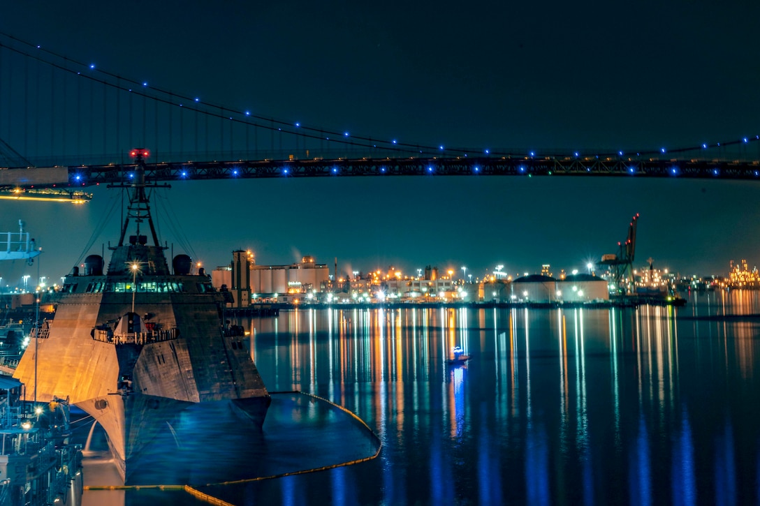 A navy ship sits in port at night.