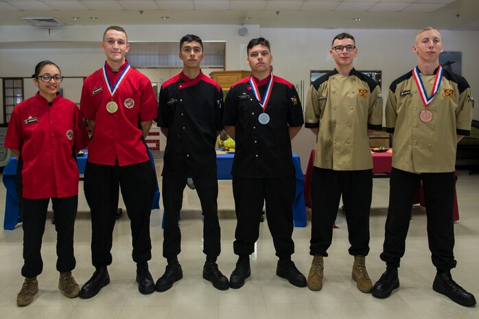 The Marines competing in the Food Specialist of the Quarter pose for a group photo at Camp Kinser, Okinawa, Japan, Aug. 30, 2018. First place winners, left, Pfc. Dominic Marimonti and Cpl. Lexus Martinez, both food service specialist with 3rd Marine Logistic Group Headquarters Regiment; second place winners, center, Lance Cpl. Zachery Lacroix, and Lance Cpl. Jairo Salgado, both food service specialist with Headquarters Battalion, 3rd Marine Division; third place winners, right, Lance Cpl. Nathaniel Lagoydespaw and Lance Cpl. Jeremy Reynolds, both food service specialist with 3rd Battalion, 12th Marine Regiment. (U.S. Marine Corps photo by Pfc. Kindo Go)