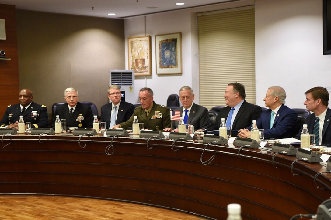 U.S. leaders sit behind a table at a meeting in India.