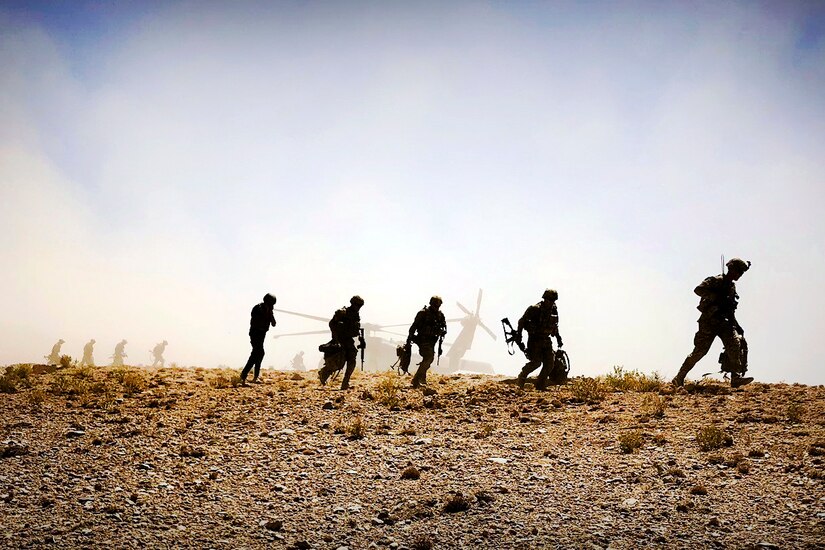Soldiers patrol the desert after leaving a Black Hawk helicopter.