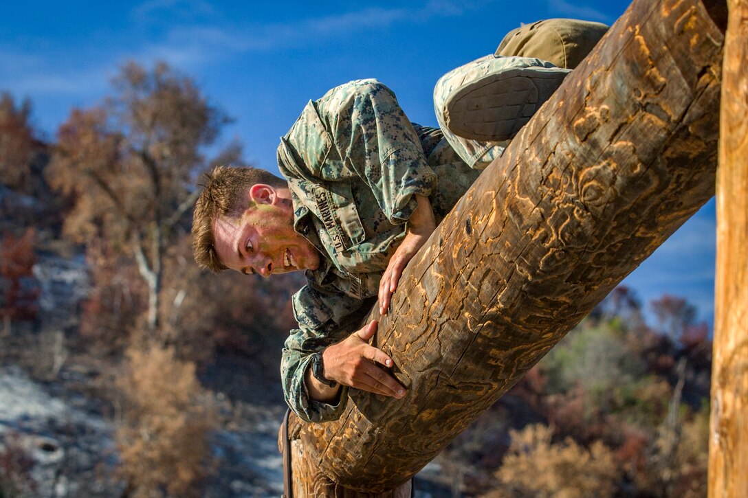 A marine climbs over a log obstacle.