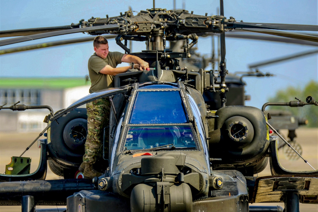 A soldier cleans a helicopter's blades.