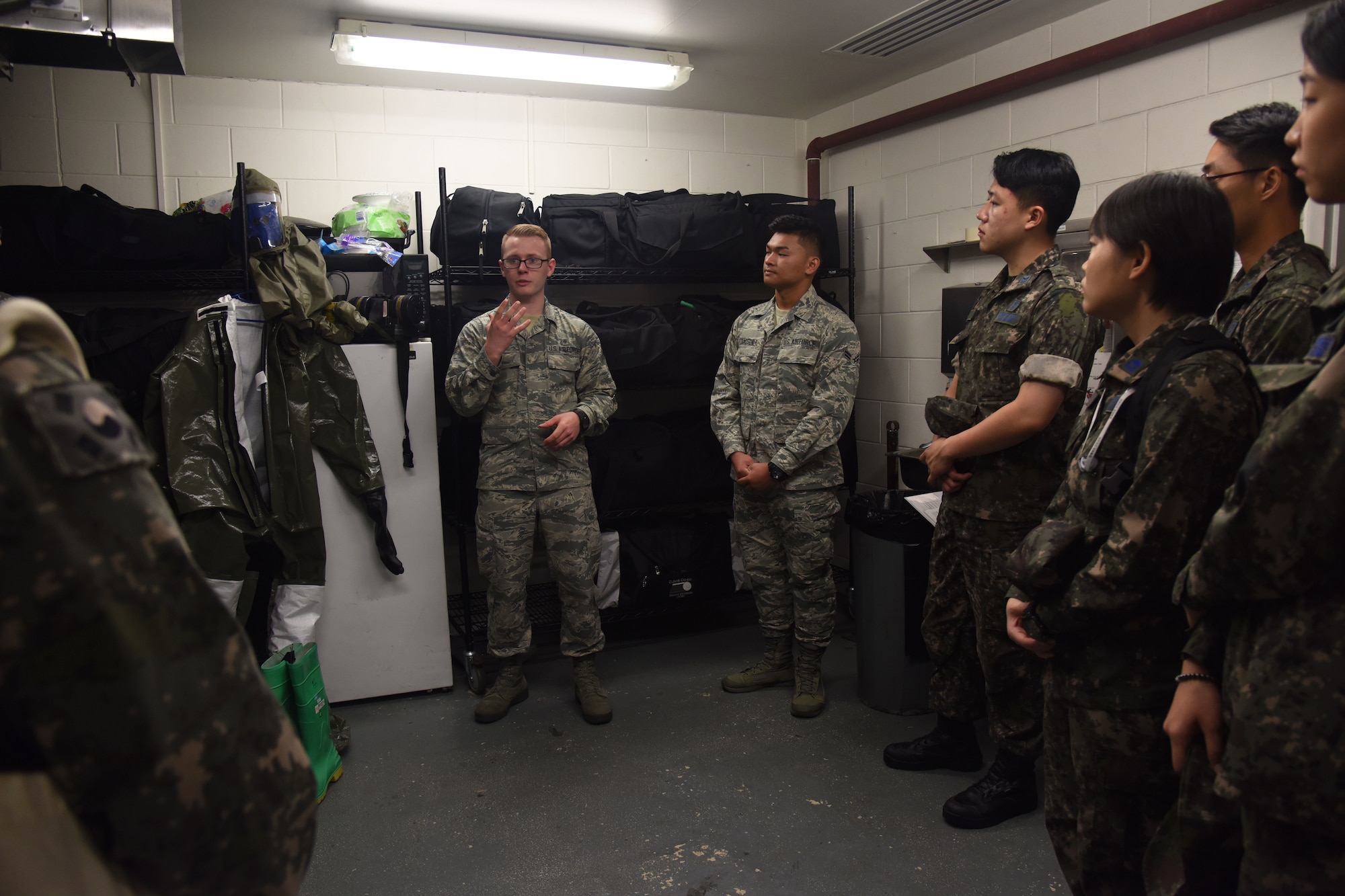 U.S. Air Force Airman 1st Class Garrett Smith, center, 51st Medical Group flight medicine technician, explains the powered air-purifying respirator suit to Republic of Korea Air Force flight technicians and nurses during a tour of the medical group’s patient decontamination area at Osan Air Base, Republic of Korea, Sept. 6, 2018. The suit is used to wear to avoid contamination to the skin in a chemical environment. (U.S. Air force photo by Tech Sgt. Ashley Tyler)