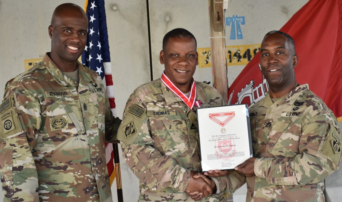 Afghanistan District Command Sergeant Major Nathaniel Atkinson and District Commander Jason Kelly present Lawrence Thomas with the DeFleury Award Certificate at Bagram Airfield. There are four levels of the de Fleury Medal: steel, bronze, silver and gold. Only one gold medal is awarded each year by the U. S. Army Chief of Engineers.