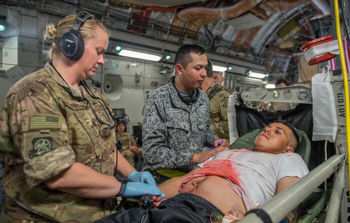 U.S. Air Force and Colombian Airmen work together to simulate providing aid to a triage patient on board a C-17 Globemaster III from Charleston Air Force Base, South Carolina, during exercise Angel de los Andes Sept. 5, 2018 at German Olano Air Base, Colombia. Airmen from Colombia, Peru, Brazil and the United States worked with Colombian firefighters and civil defense team to air evacuate more than 25 people during a simulated aircraft crash. (U.S. Air Force photo by Staff Sgt. Robert Hicks)
